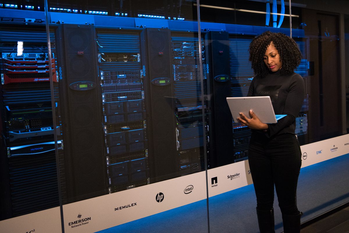 Specialist documenting hardware in front of enterprise server racks